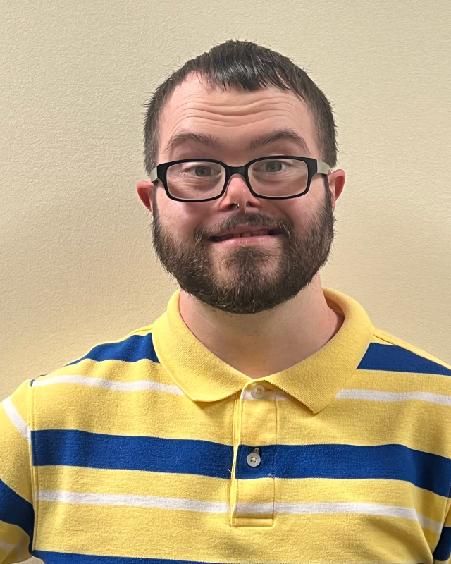 young man with beard, glasses, and yellow striped shirt