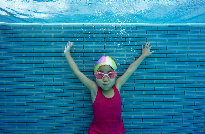 Small girl swimming underwater giving a thumbs up